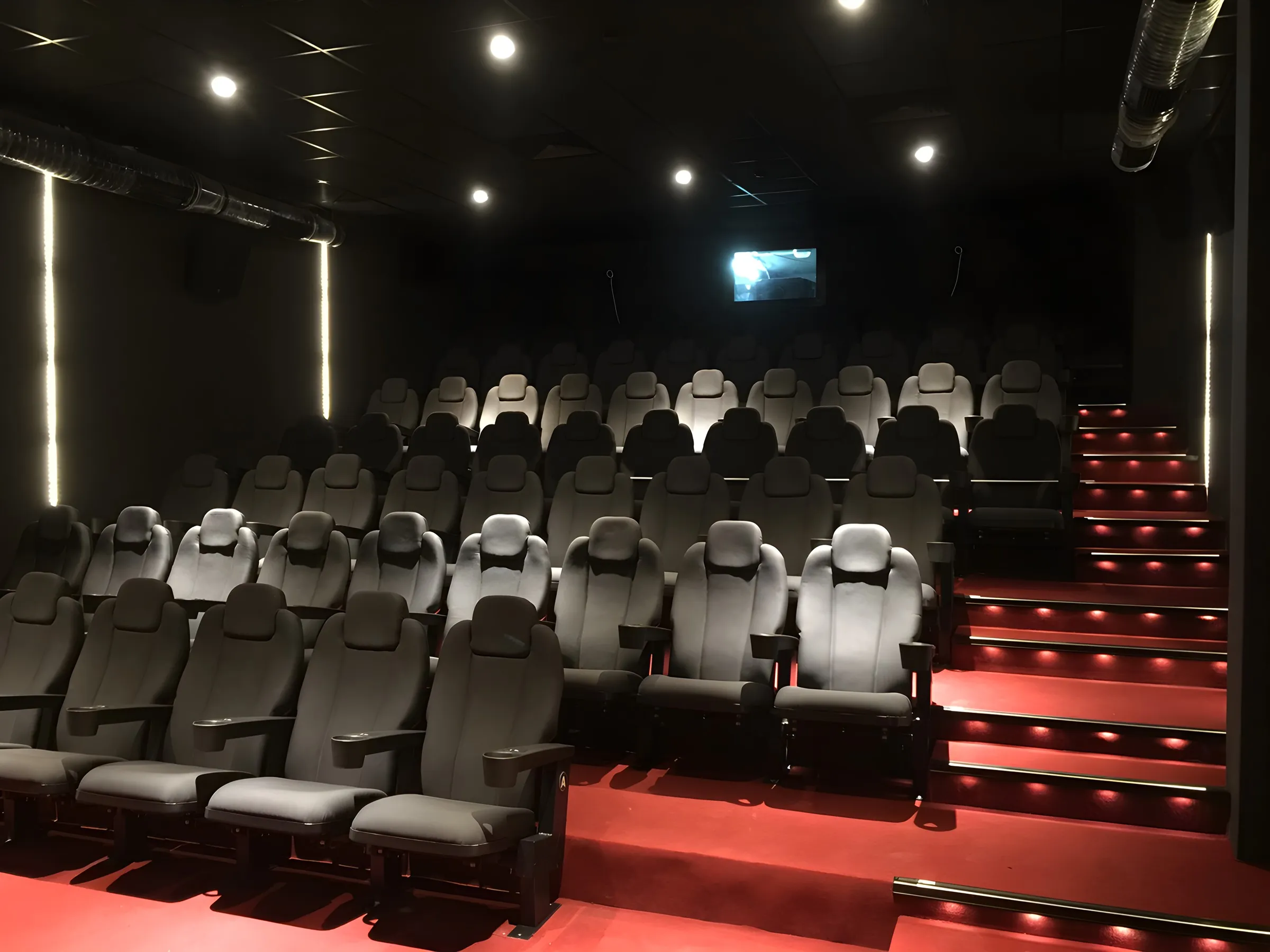 Avenue Cinemax salonu: gri koltuklar ve kırmızı ışıklı basamaklar